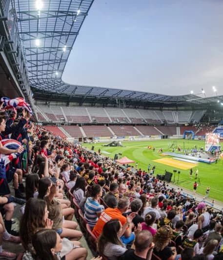 Nächtliche Zeremonie bei den United World Games mit Feuerwerk und jubelnden Zuschauern in einem großen Stadion.