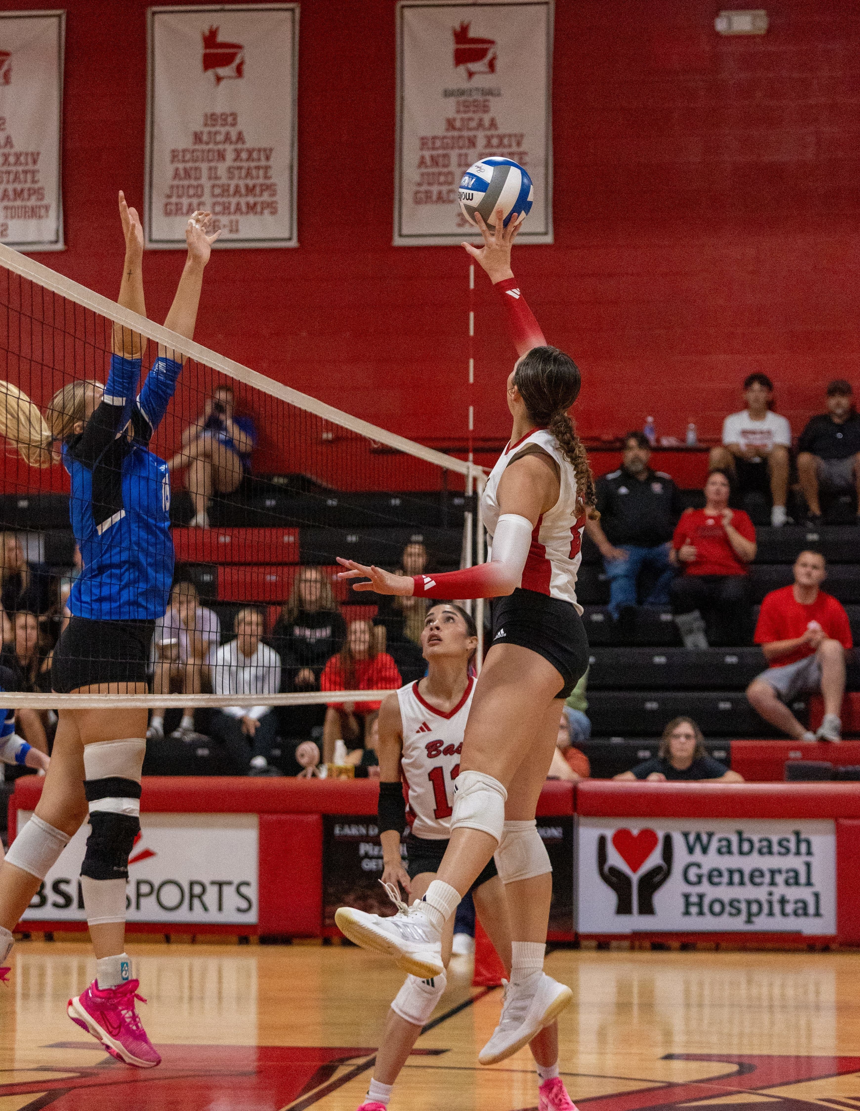 College-Volleyballspielerin springt, um den Ball über das Netz zu schlagen.