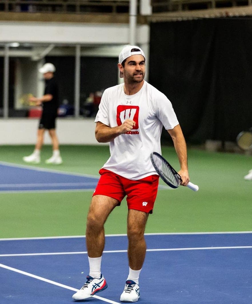 College-Tennisspieler feiert einen Punkt | Smarthlete Männlicher College-Tennisspieler feiert seinen Punkt mit geballter Faust.