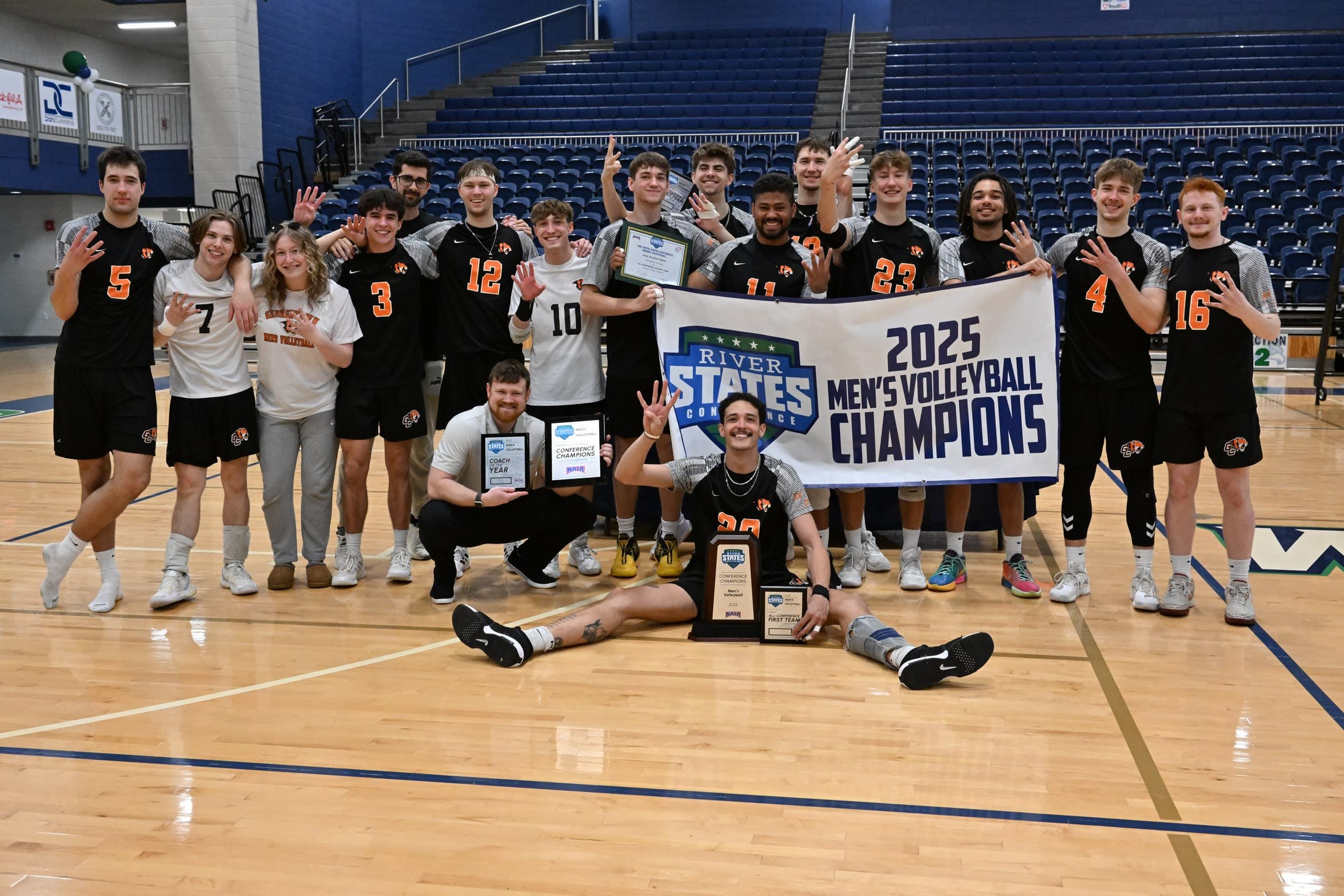 College-Volleyballteam feiert Meisterschaft | Smarthlete College-Volleyballteam feiert eine Meisterschaft mit Banner und Trophäe.