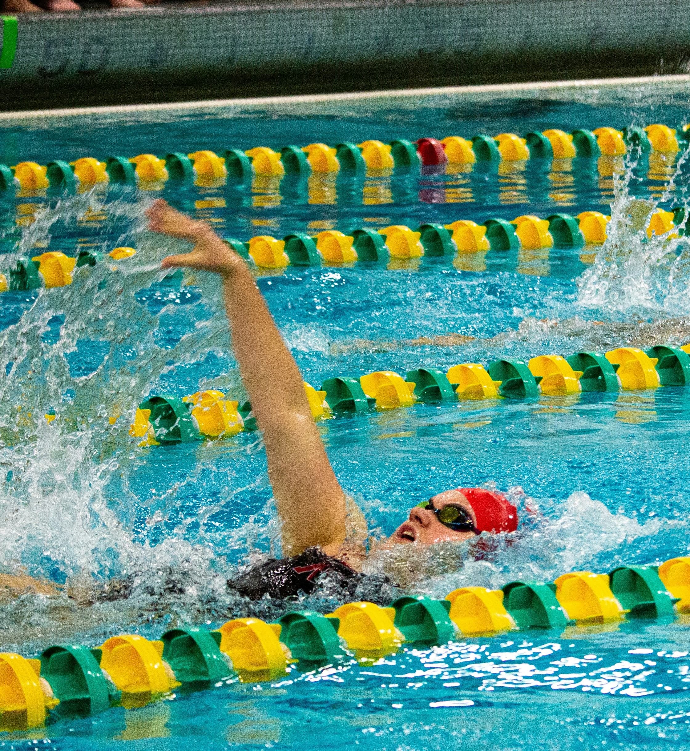 Weibliche College-Schwimmerin beim Rückenschwimmen | NCAA-Rennen Weibliche College-Schwimmerin beim Rückenschwimmen im Rennen.